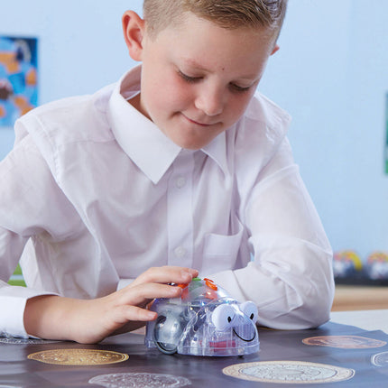 Élève programmant le Blue-Bot avec les flèches de son dos sur un tapis de jeu